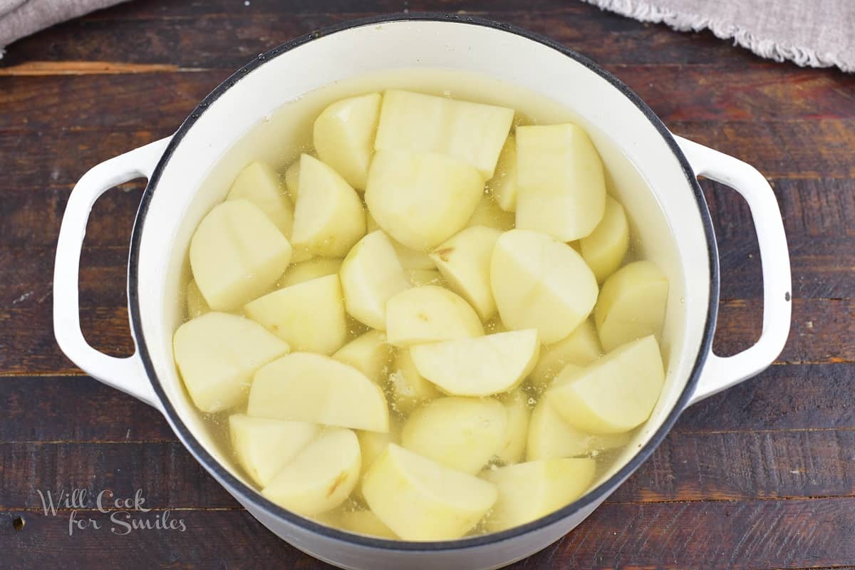 cut potatoes in water in a white pot.
