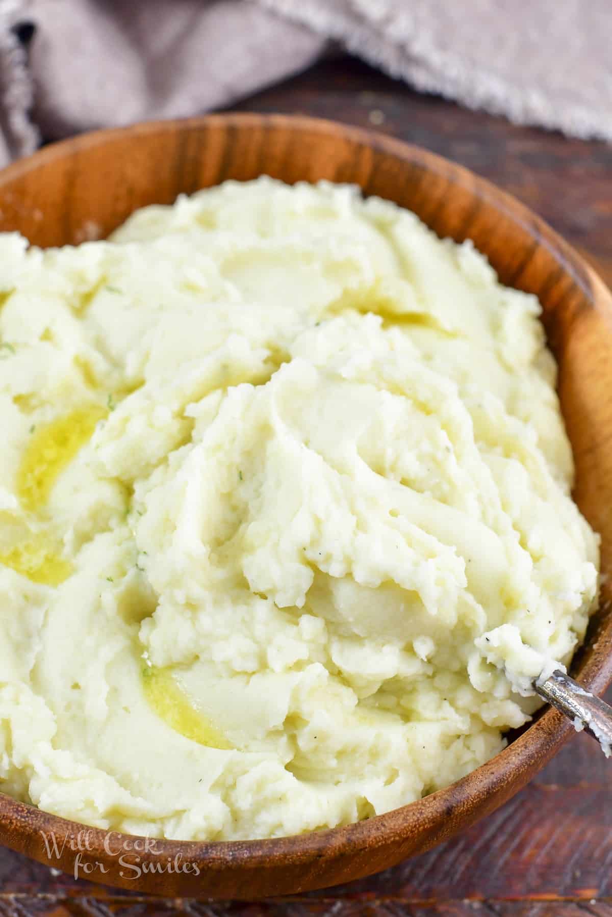 scooping some mashed potatoes out of the wooden bowl.