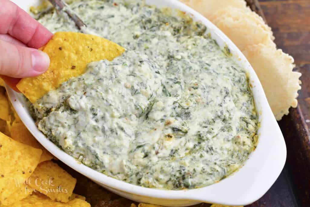 scooping some of the creamy spinach dip with tortilla.