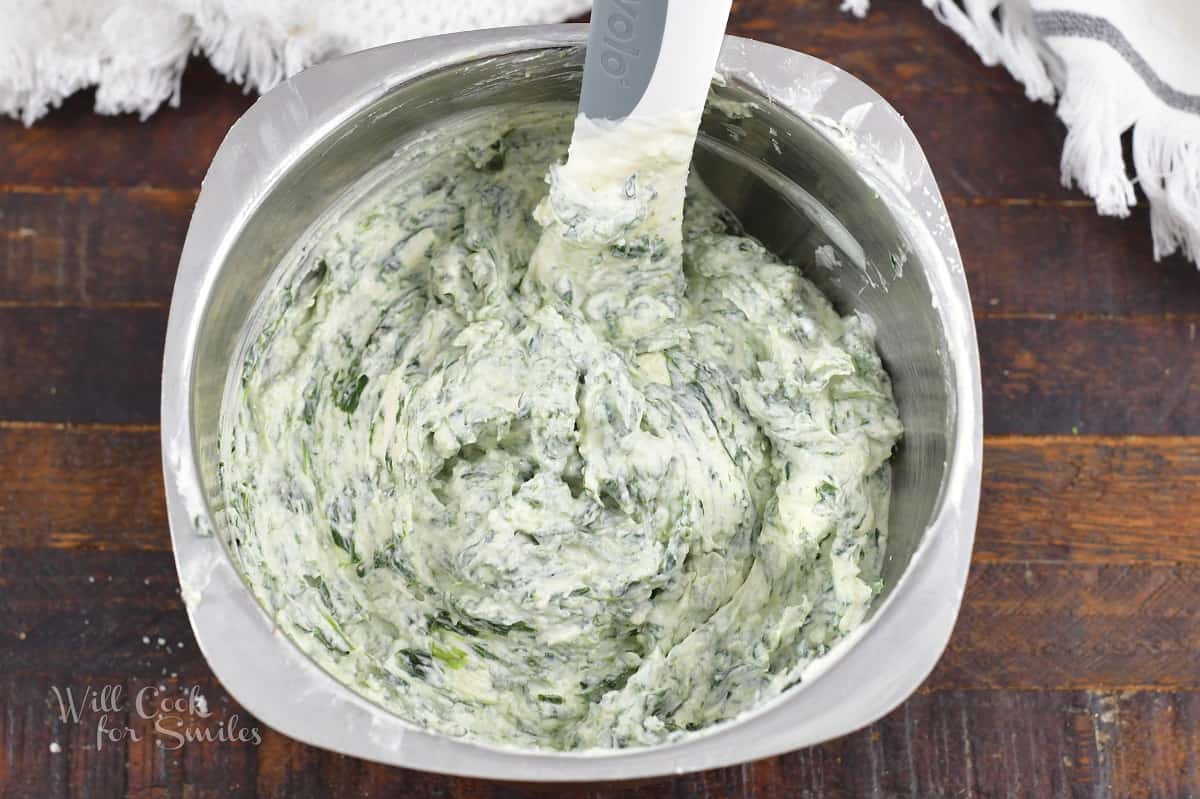 mixing the spinach dip ingredients in a metal bowl.