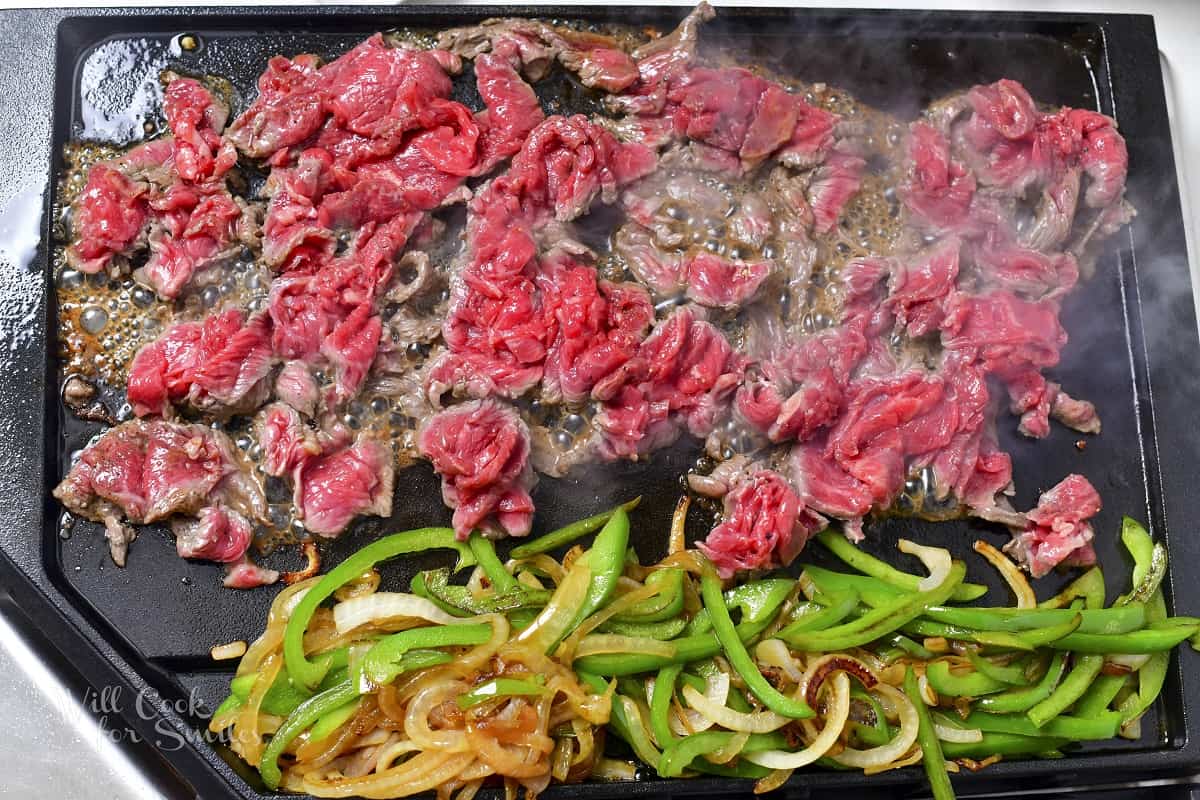 steaks searing next to onion and peppers