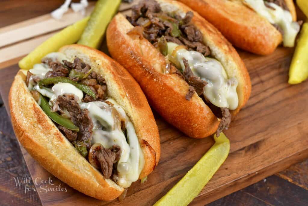 cheesesteak sandwiches with pickles on the board