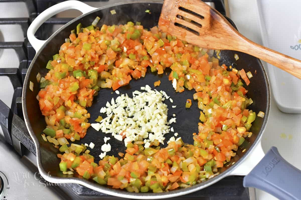 adding minced garlic to the pan with vegetables