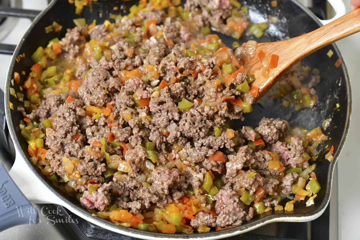mixing ground beef with vegetables in the pan