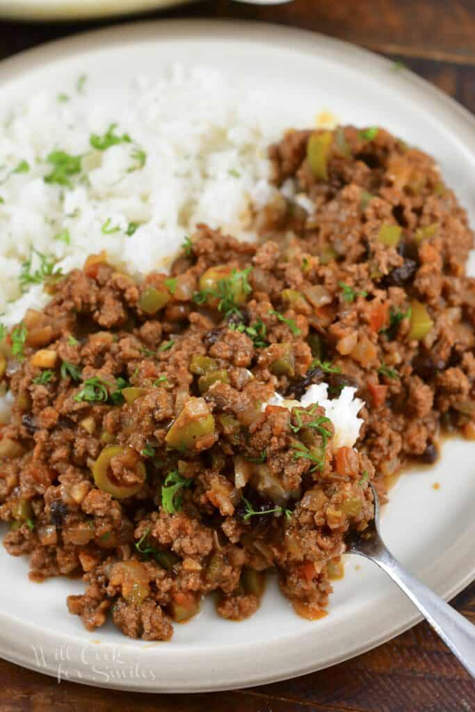 scooping some meat and rice with a fork on the plate