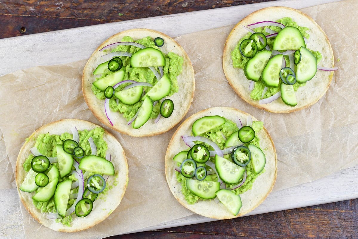 four tortillas topped with guacamole and veggies