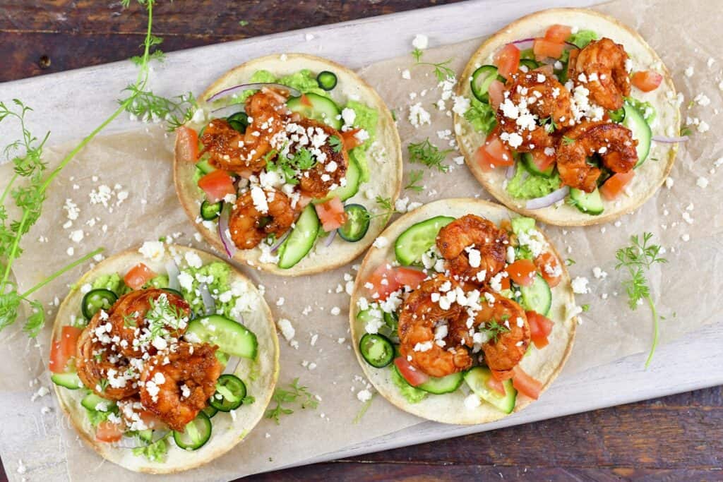 four tostadas with shrimp and veggies on the board
