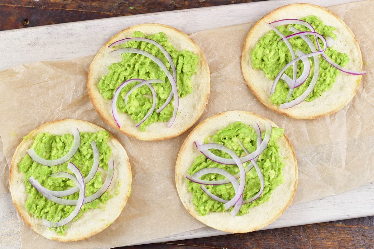 tortillas topped with some guacamole and red onion