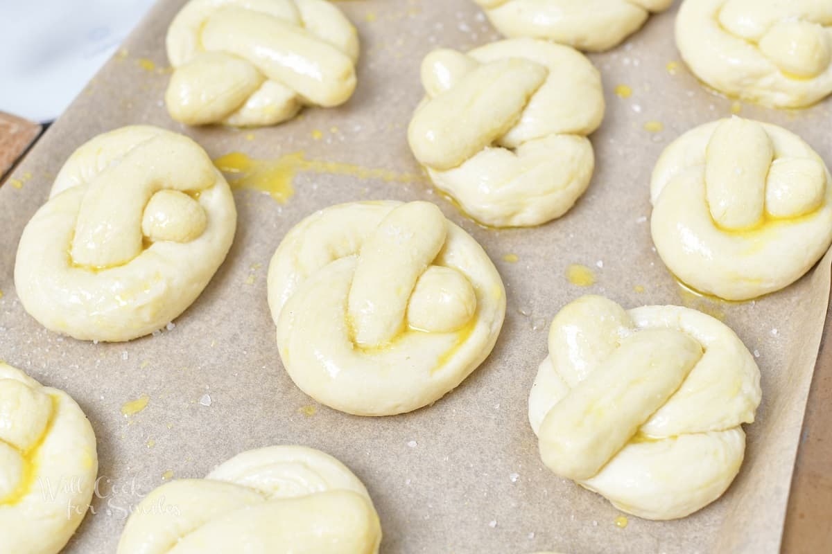 uncooked pretzels on baking tray with butter and salt.