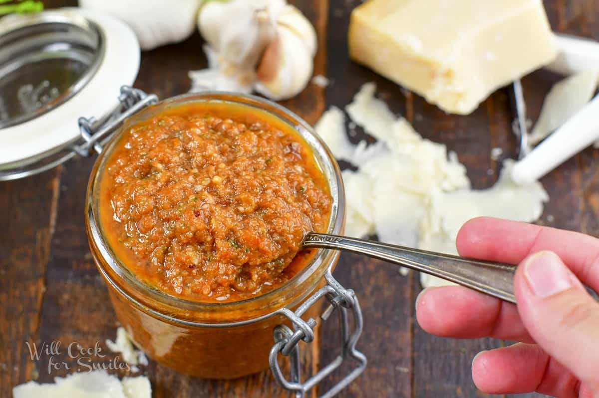 closeup scooping out some pesto rosso out of the jar