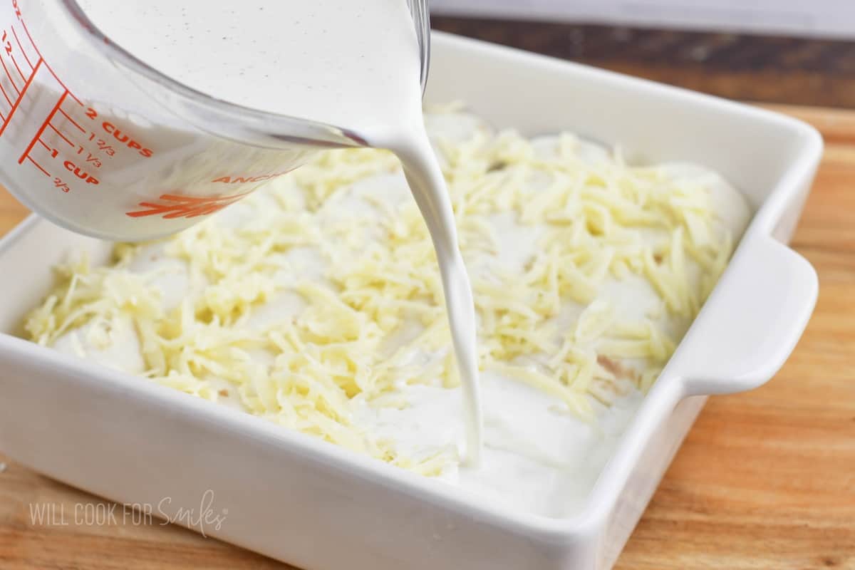 adding cream mixture to the rolled enchiladas in a dish.