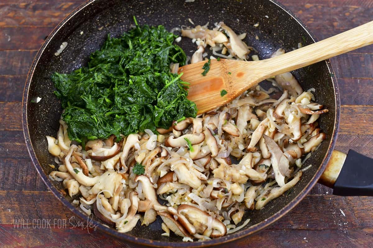 spinach mushrooms and onions cooked in a pan.