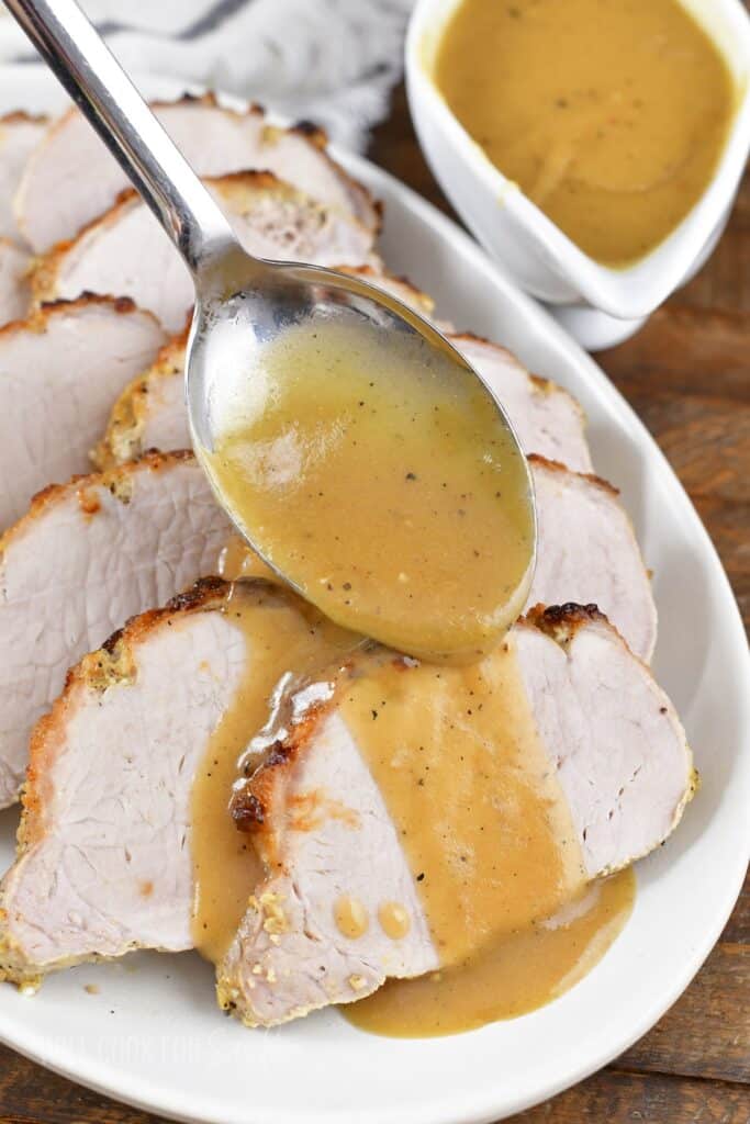 spreading gravy over the sliced pork.