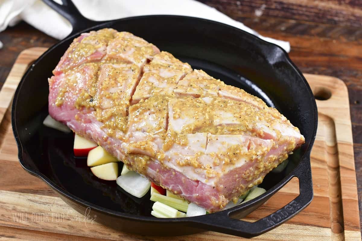 seasoned pork loin in a skillet on bed of beggies.