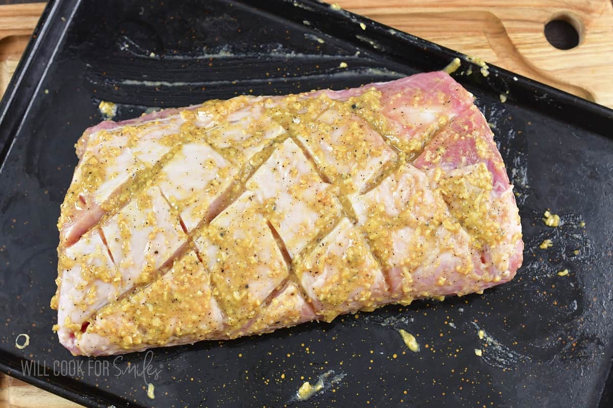 pork loin coated in maple Dijon wet rub on the tray.