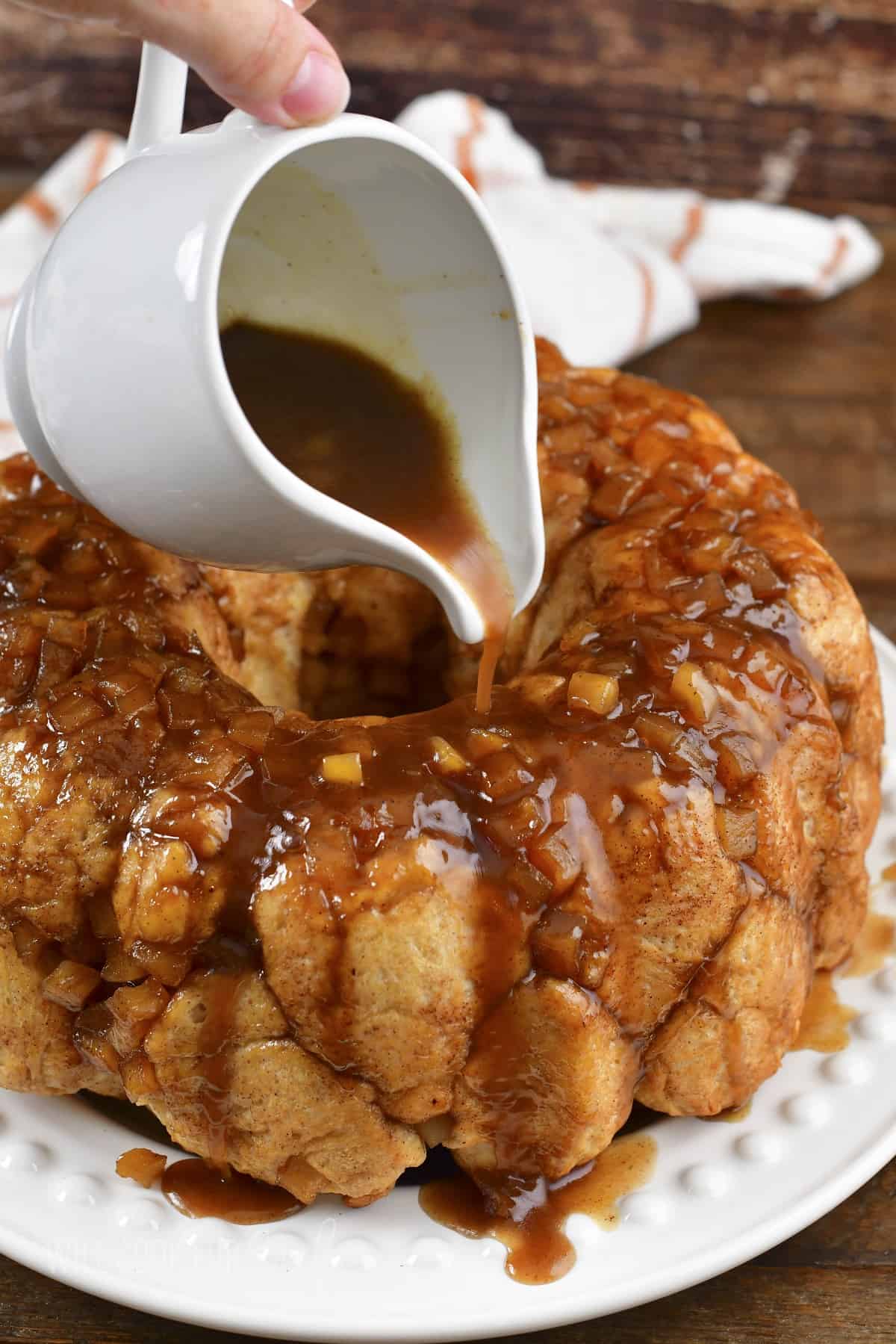 pouring sauce over the monkey bread on the plate.