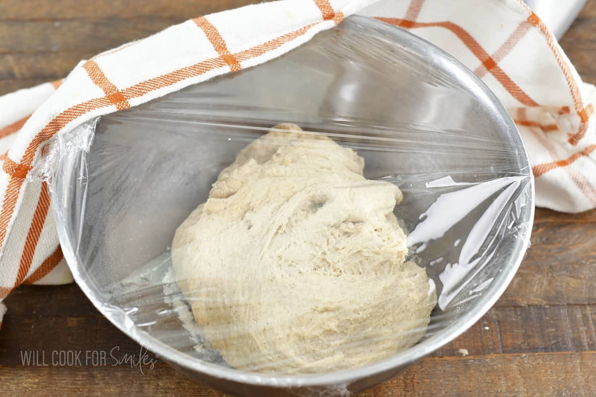 dough in a bowl covered with plastic wrap.