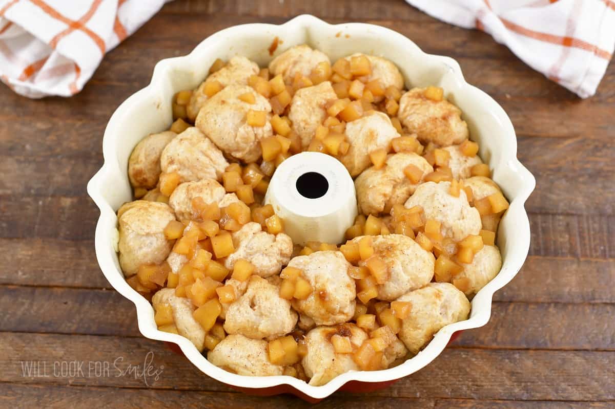 raised dough balls in bundt pan with apple topping.