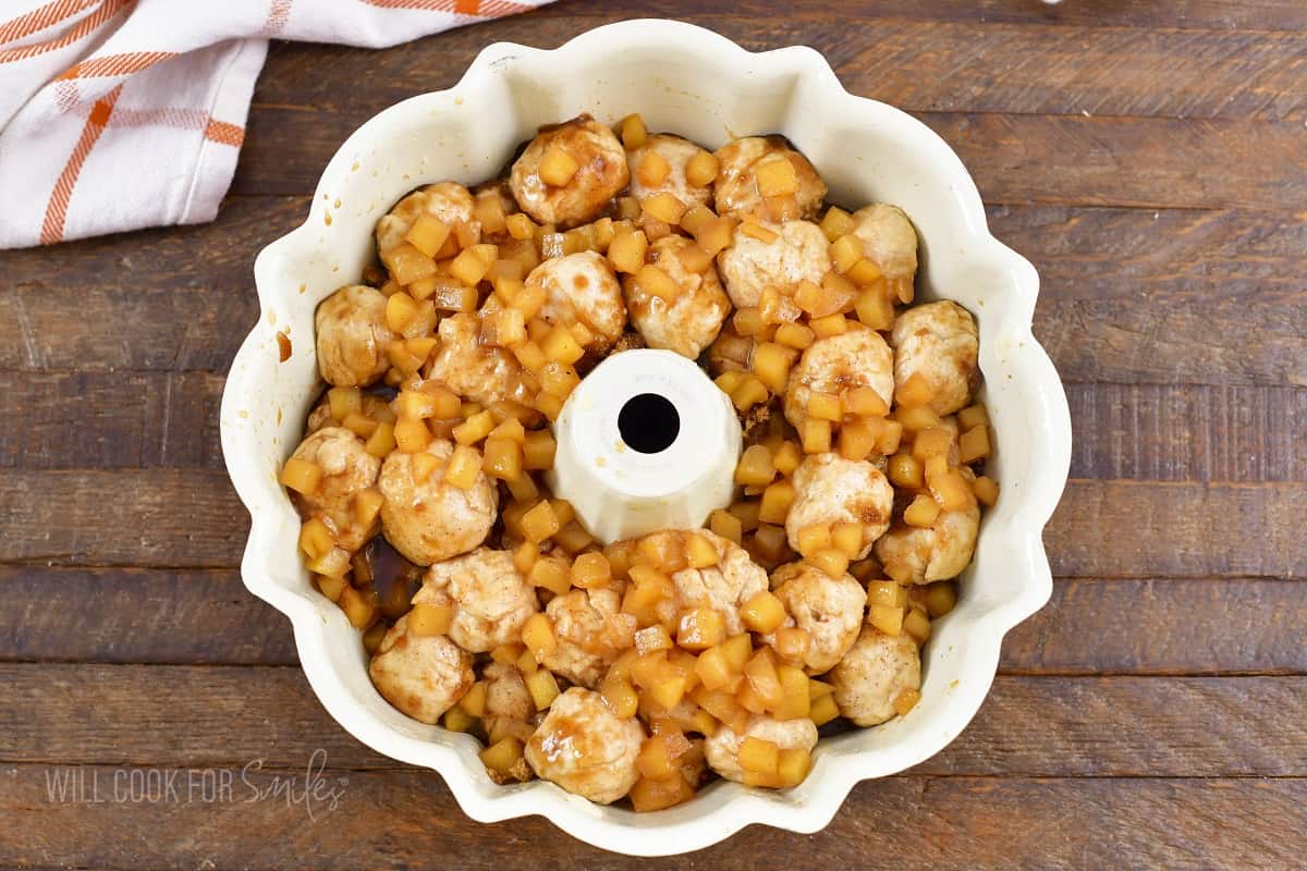 dough balls in the bundt pan with apple topping.