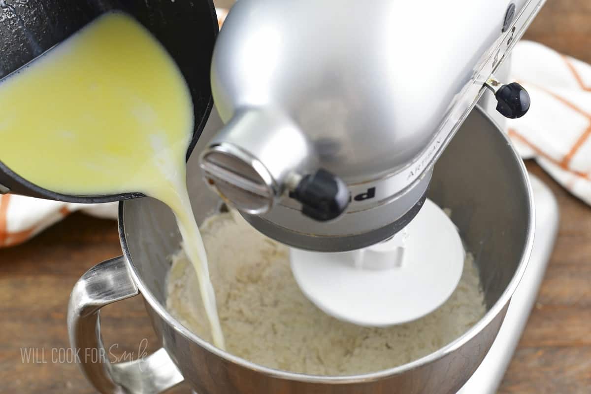 adding warm milk mixture to the mixer with flour.