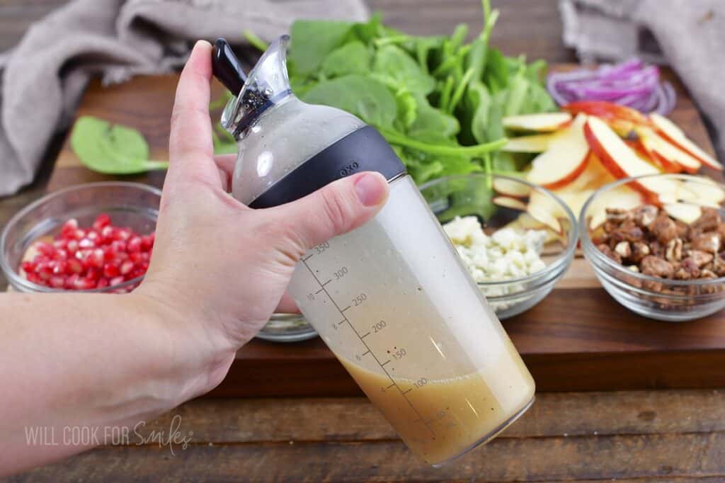 shacking the apple cider dressing in a bottle.