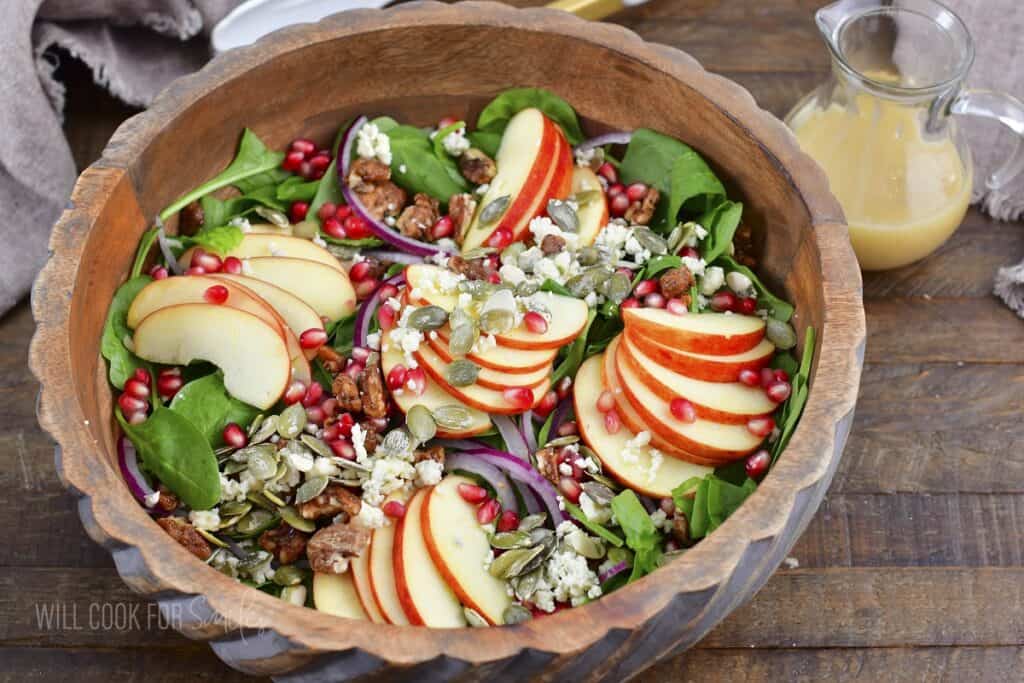 closeup of apple salad and dressing next to the bowl.