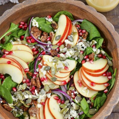 top view of apple salad in wooden bowl and dressing.