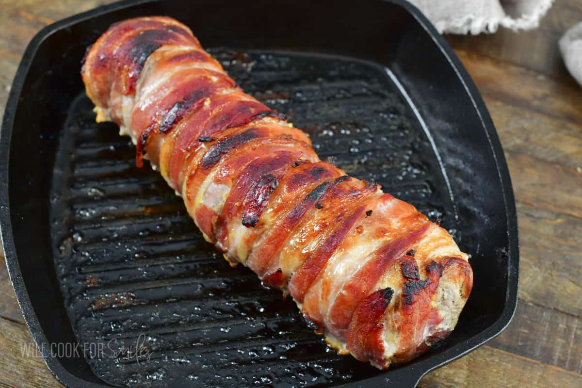 baked bacon wrapped pork tenderloin in skillet.
