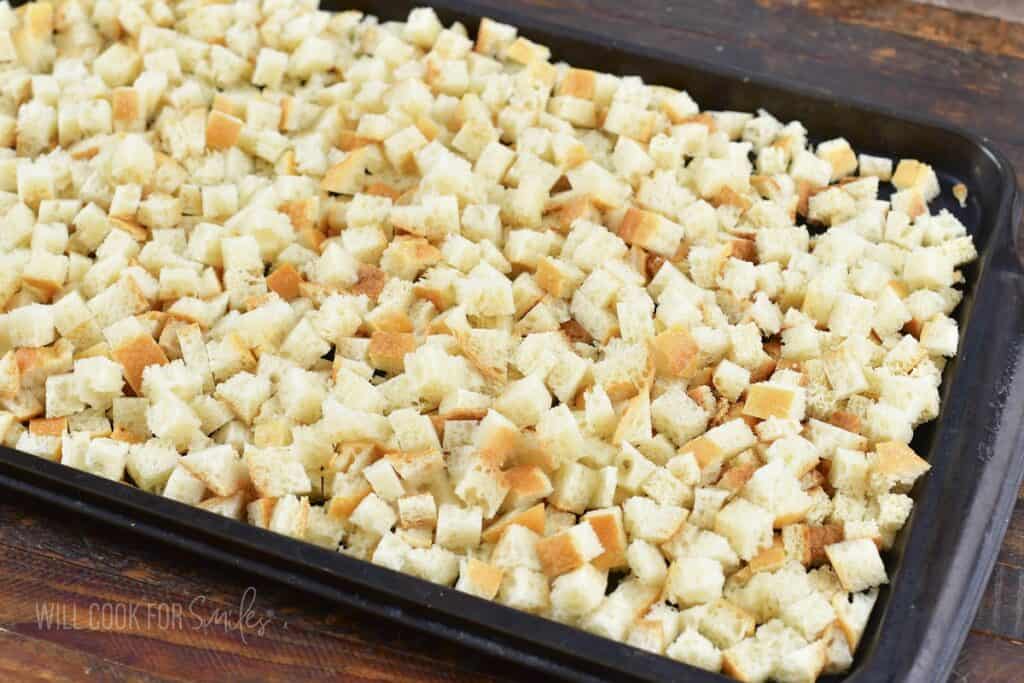 many small pieces of bread spread in a baking sheet.