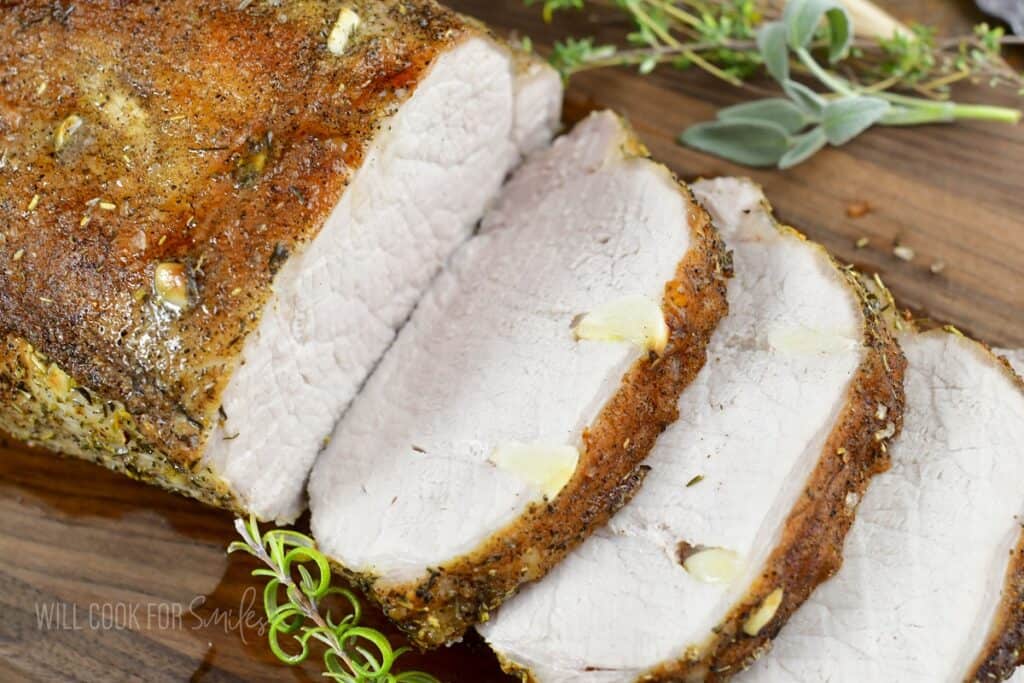 pork loin sliced with garlic visible and herbs.