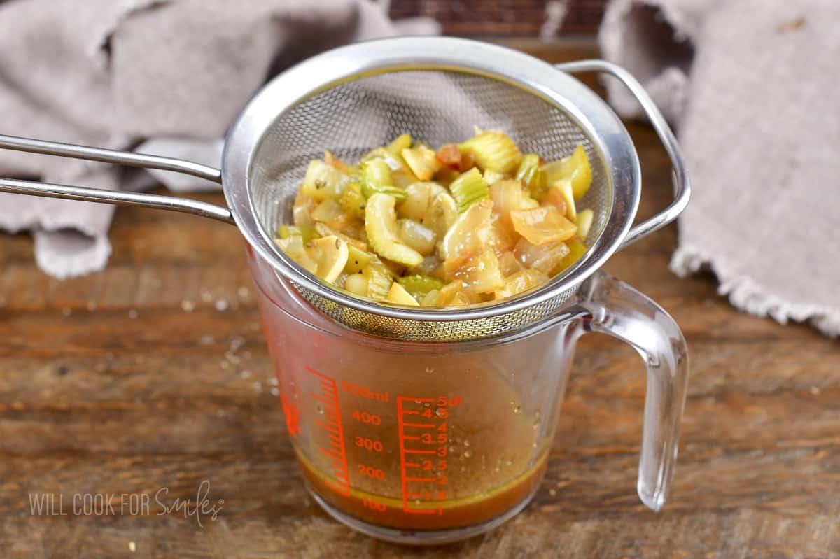 cooked veggies in mesh strainer over the measuring cup.