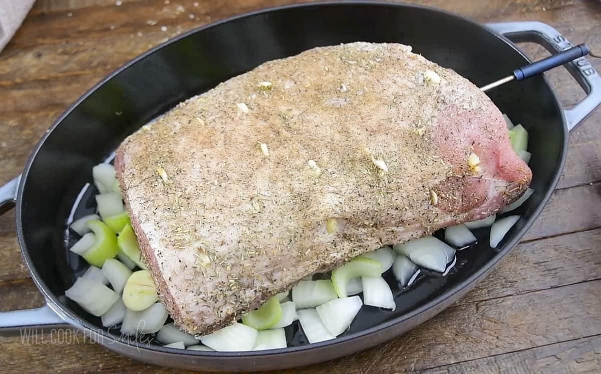 uncooked pork loin in the roasting pan over veggies.