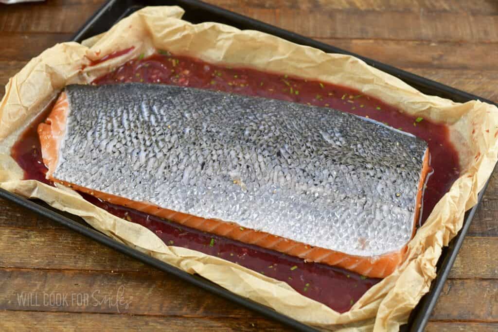 salmon filet skin side up in baking dish in sauce.