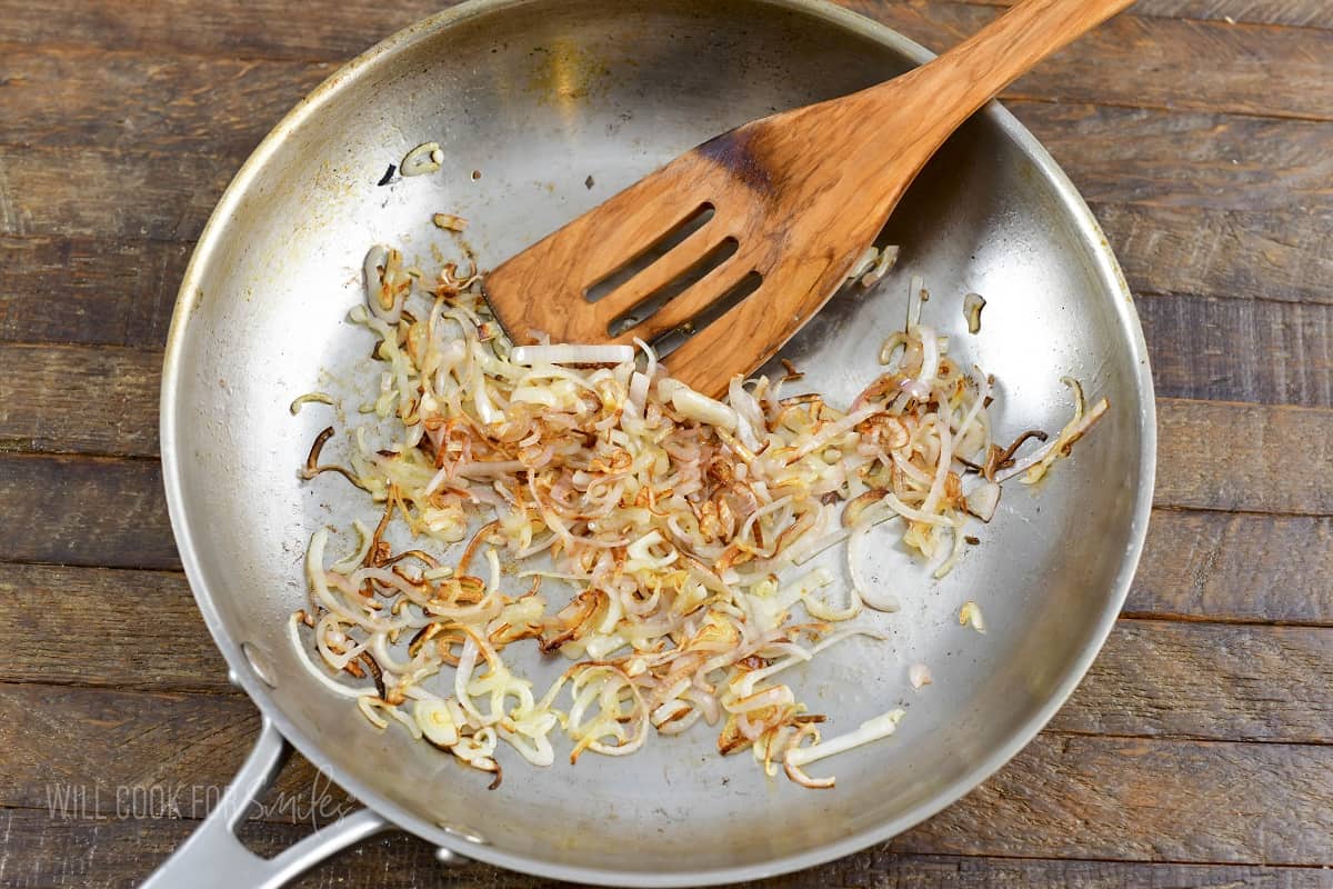 sautéed shallots in a stainless steel pan with spatula.