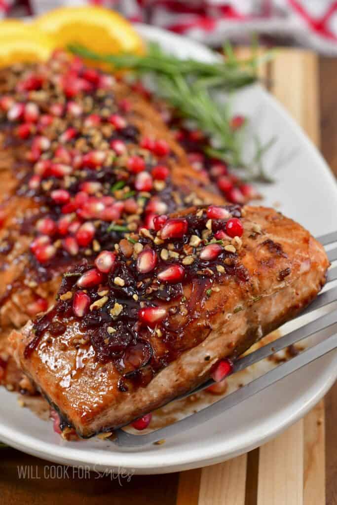 taking off a slice of pomegranate baked salmon from the dish.