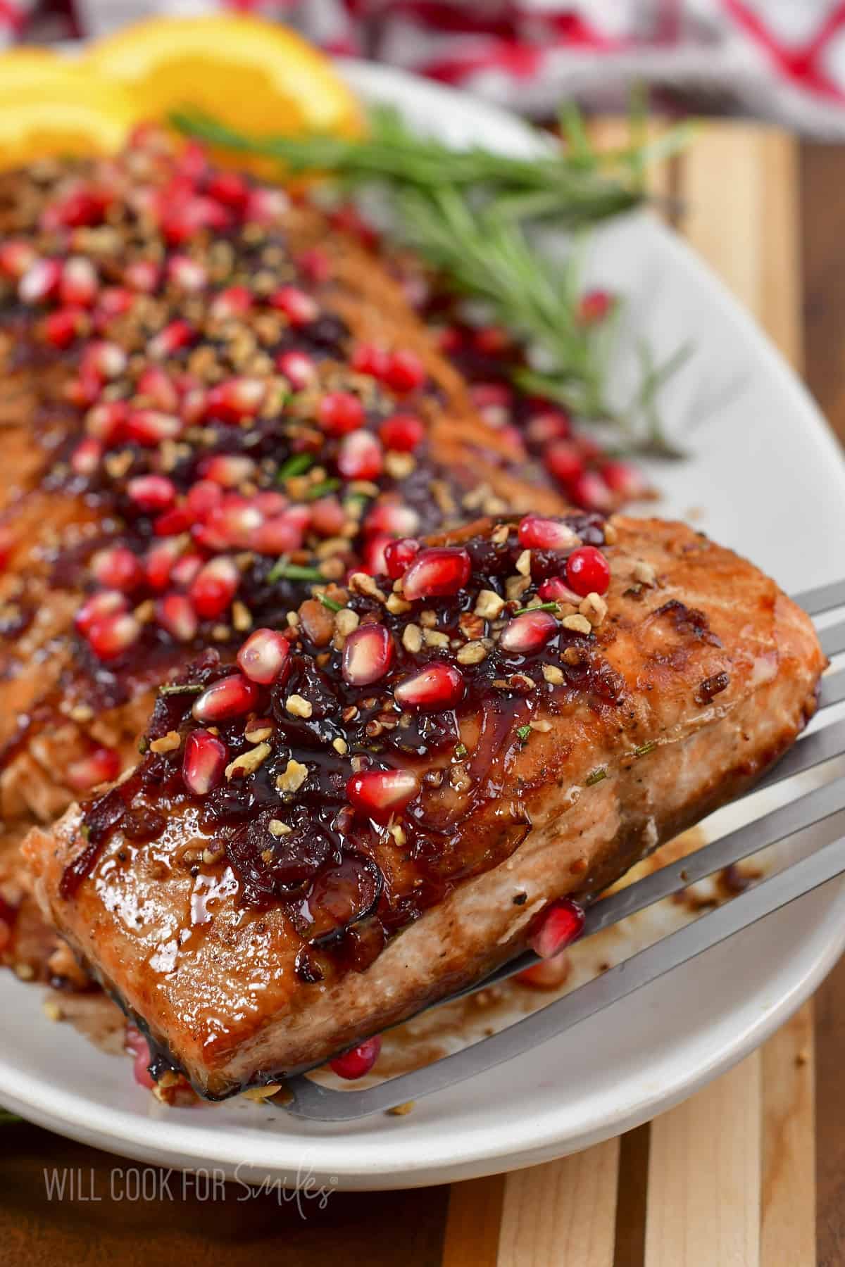 taking off a slice of pomegranate baked salmon from the dish.