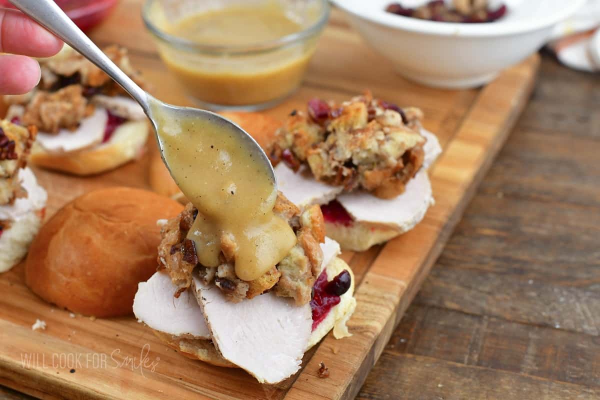 adding gravy over the stuffing on a slider.