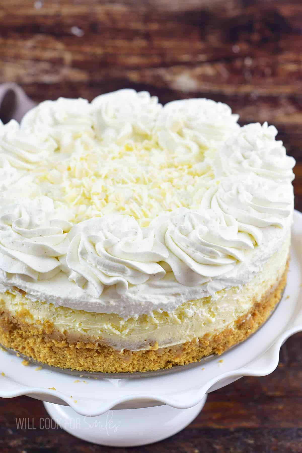 vanilla bean cheesecake with whipped cream on the cake stand.