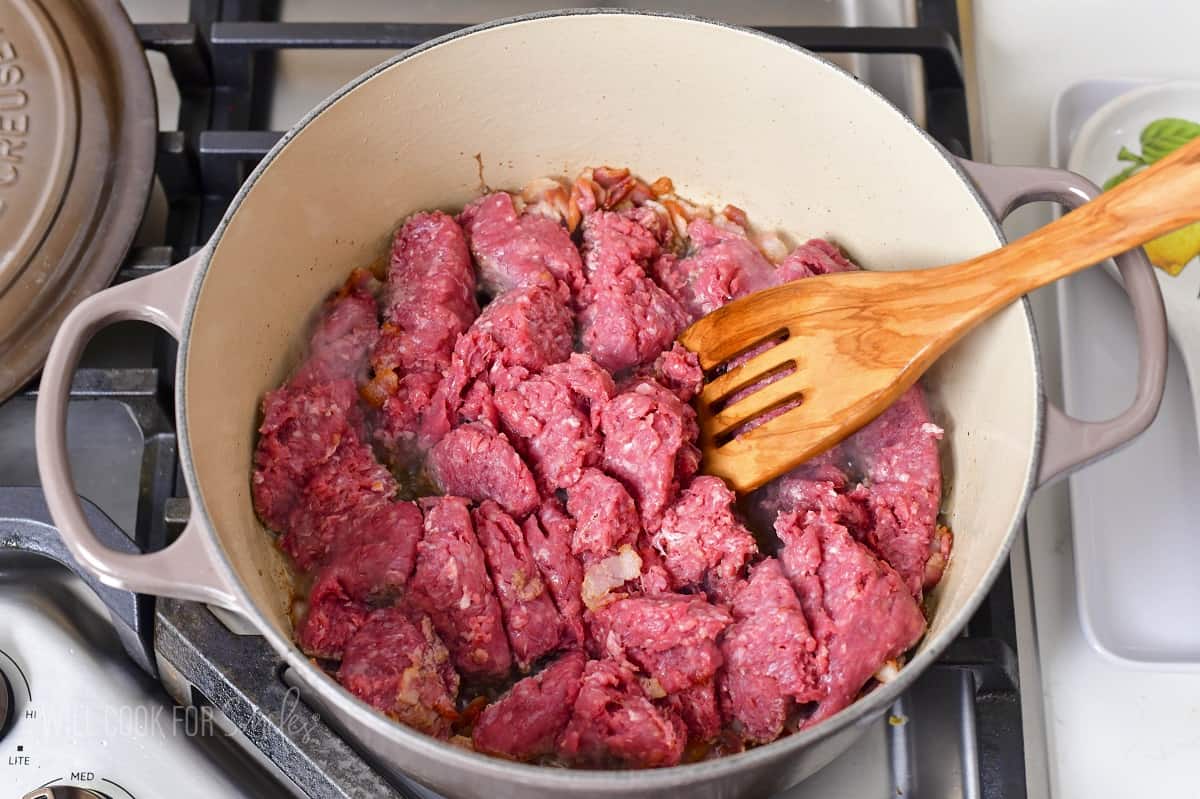 breaking up ground beef to sear it in a pot.