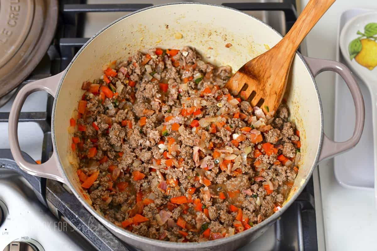 stirring seared veggies and ground beef together.
