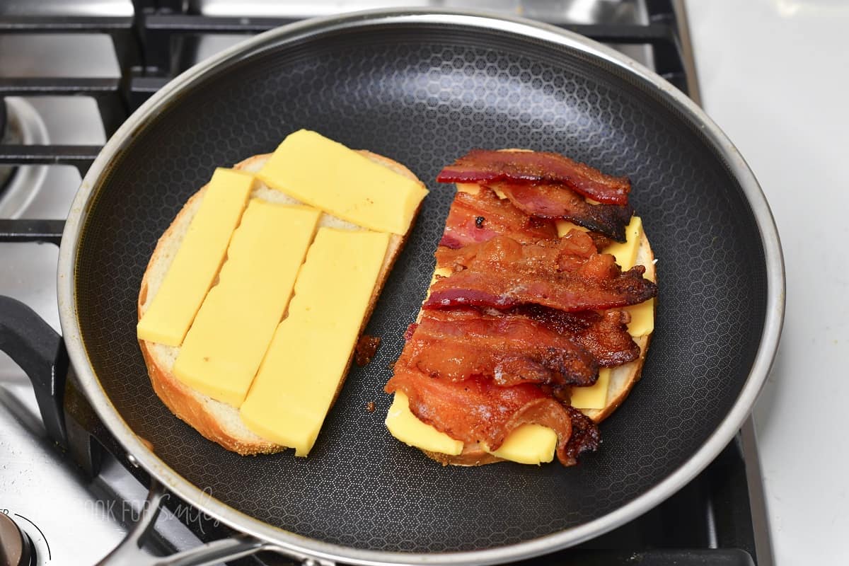 two slices of bread in the pan with cheese and one with bacon.