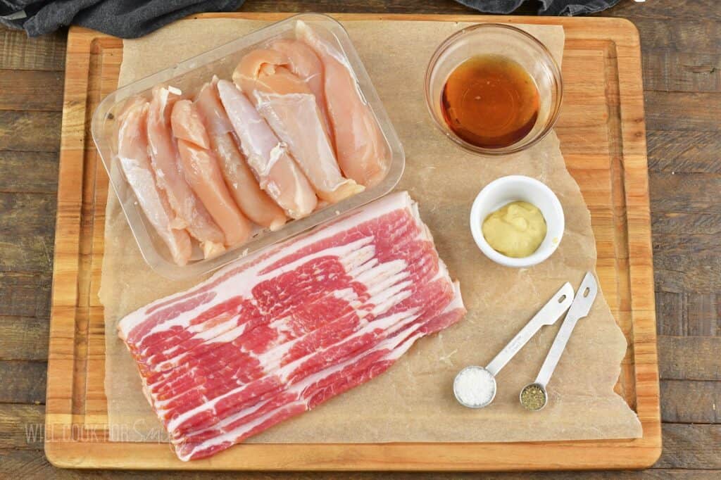 ingredients to make bacon wrapped chicken tenders on cutting board.