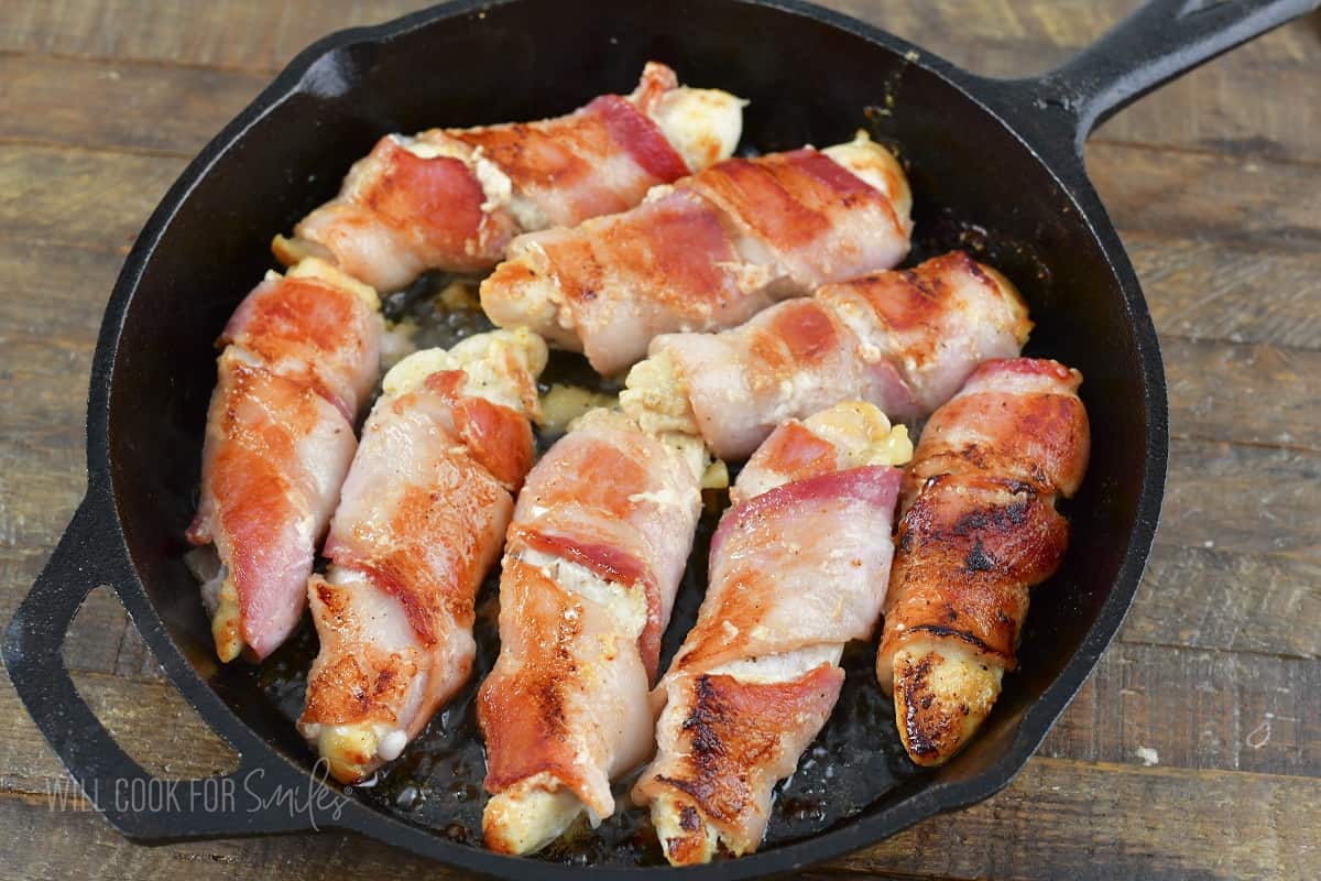 seared bacon wrapped tenders in a skillet before baking.