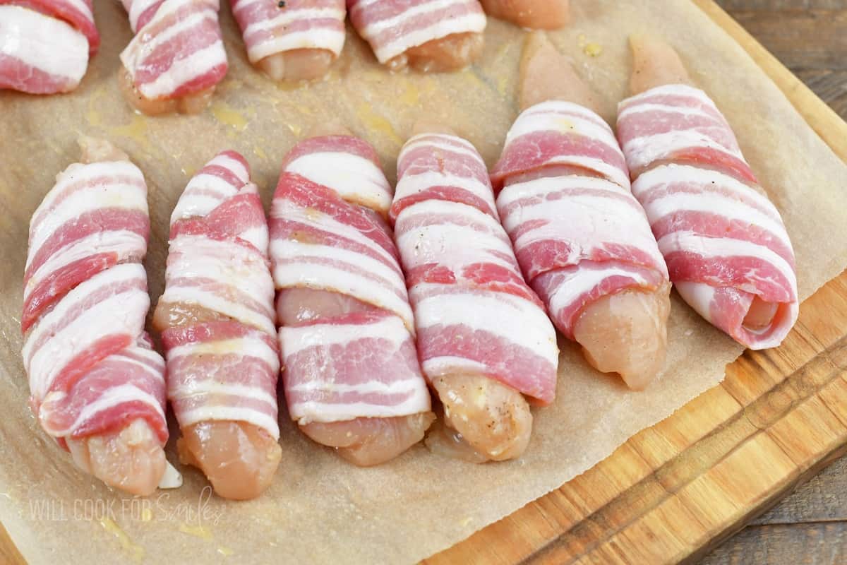 bacon wrapped chicken tenders side by side on parchment.