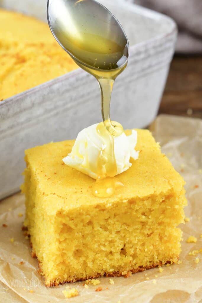 adding honey over the square of cornbread and butter.