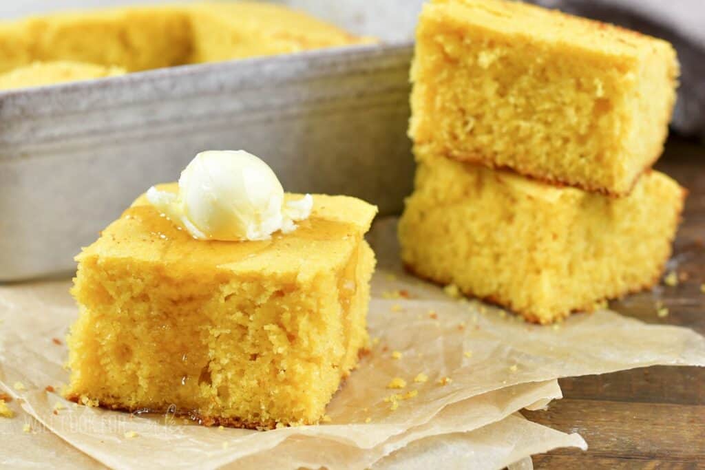 cornbread square with butter and honey next to two stacked.