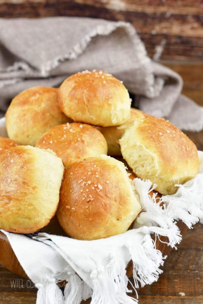 side view of dinner rolls in a wooden bowl with towel.