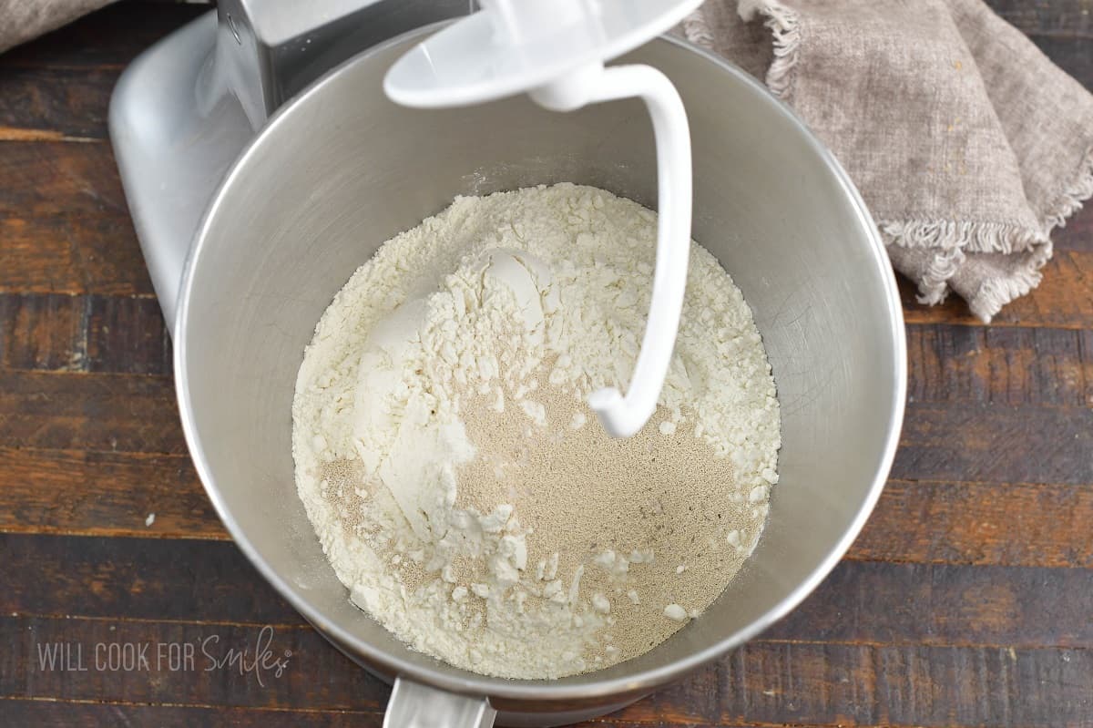 flour, sugar, salt, and yeast in a bowl of a mixer.