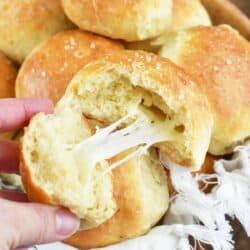 pulling part a dinner roll to show the cheesy center.