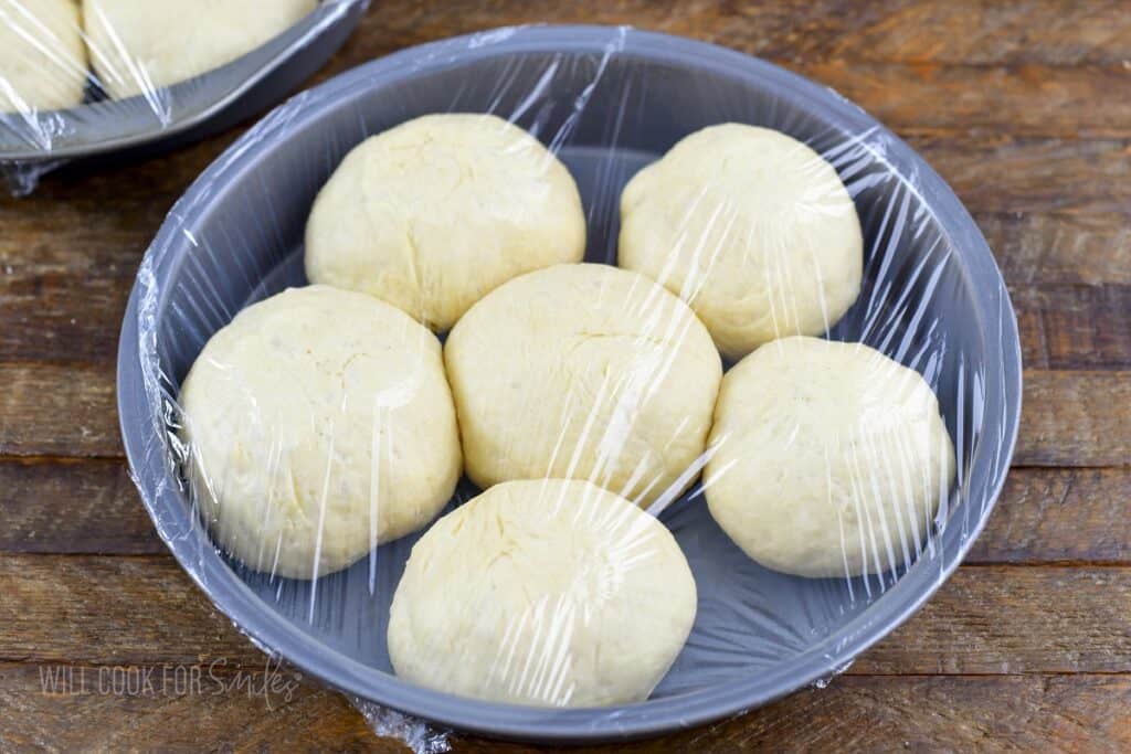 raised rolled dough pieces in a covered baking dish.